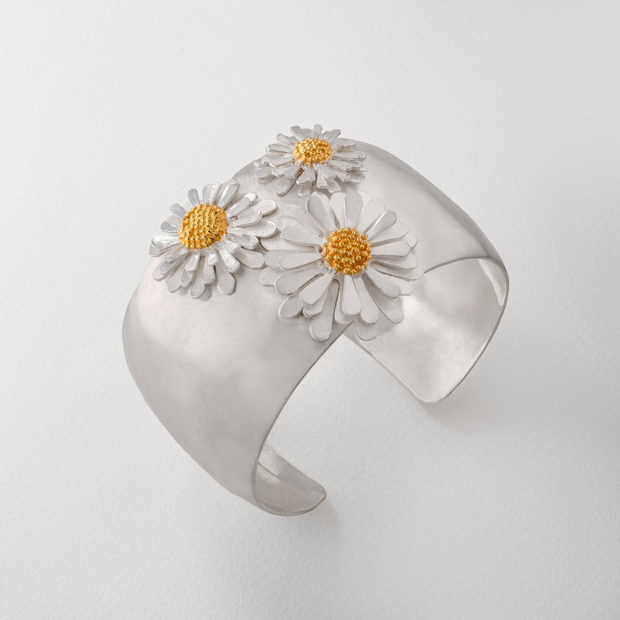 Silver cuff bracelet bangle with three aster flowers with 18ct gold accents.