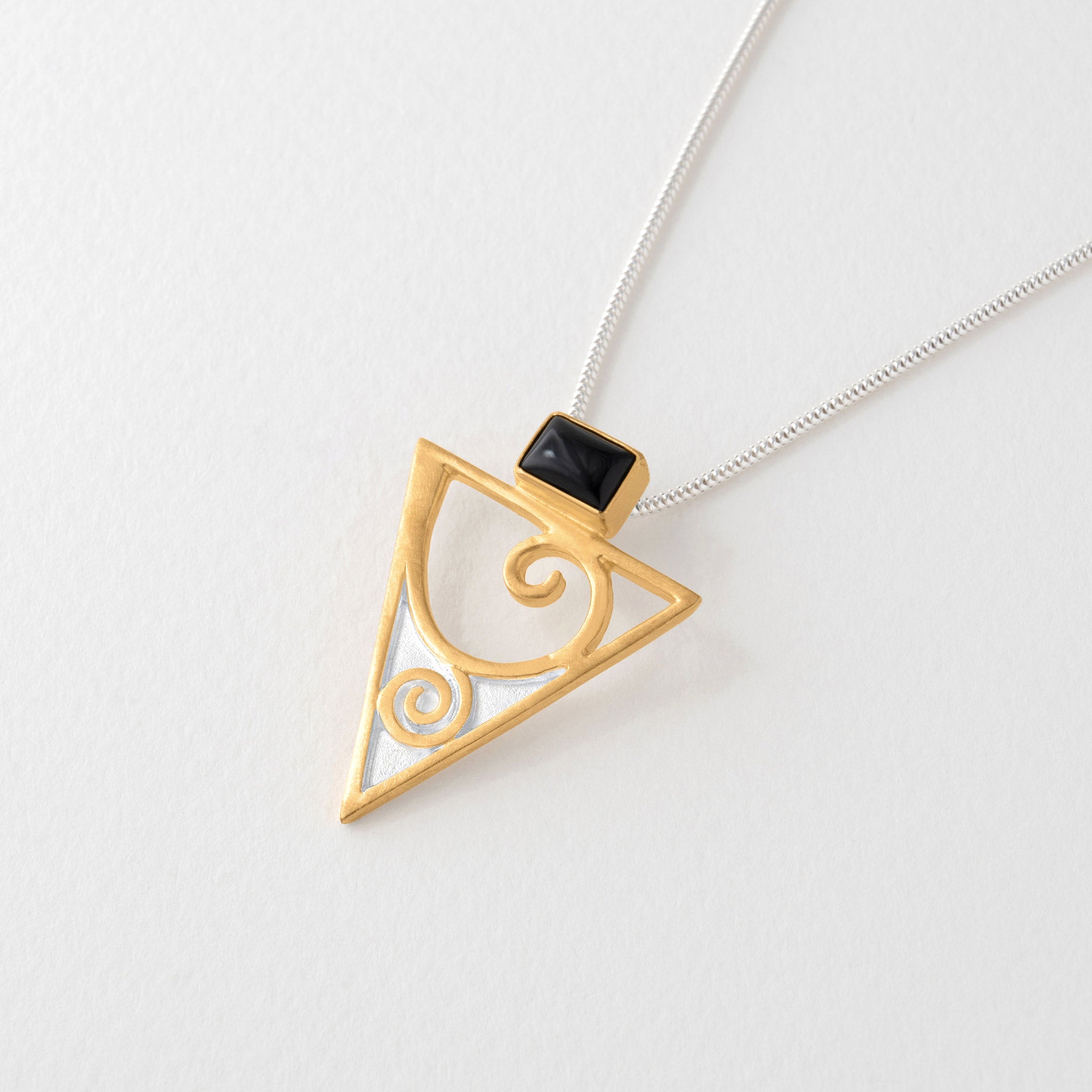 Gold triangular pendant necklace inspired by Gustav Klimt. Swirling gold and triangular design with black onyx.