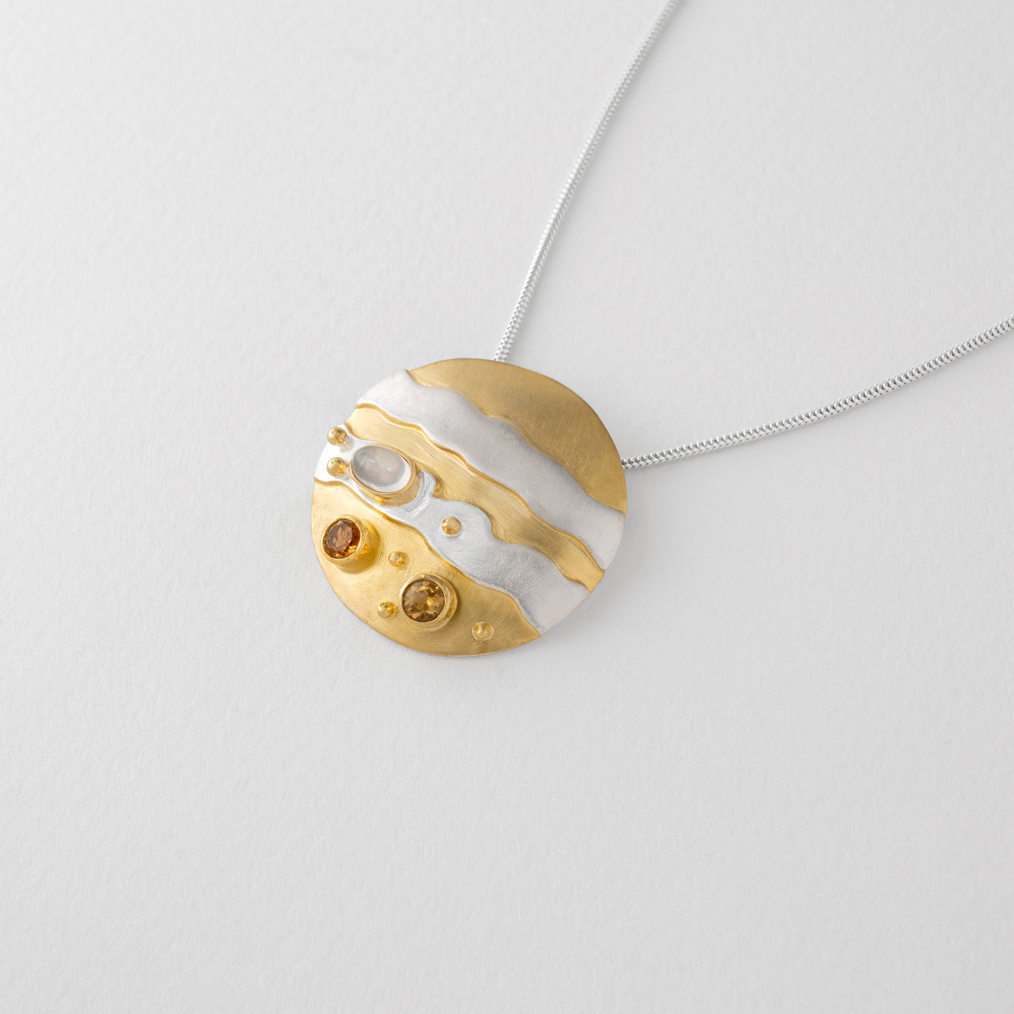 A Jupiter planet necklace in sterling silver and gold plate with moonstone and citrine gems