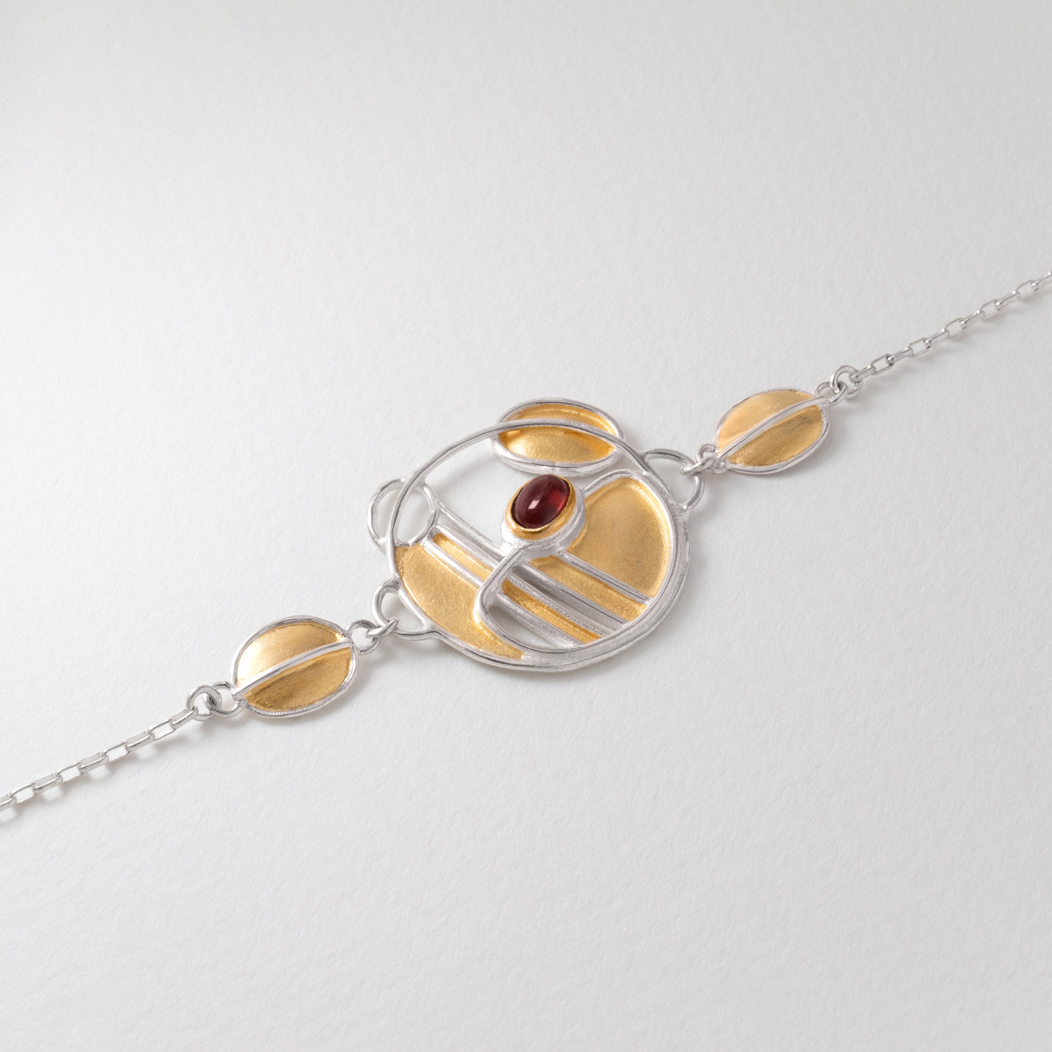 Charles Rennie Mackintosh inspired bracelet in sterling silver with 18ct gold plate and garnet gemstone.