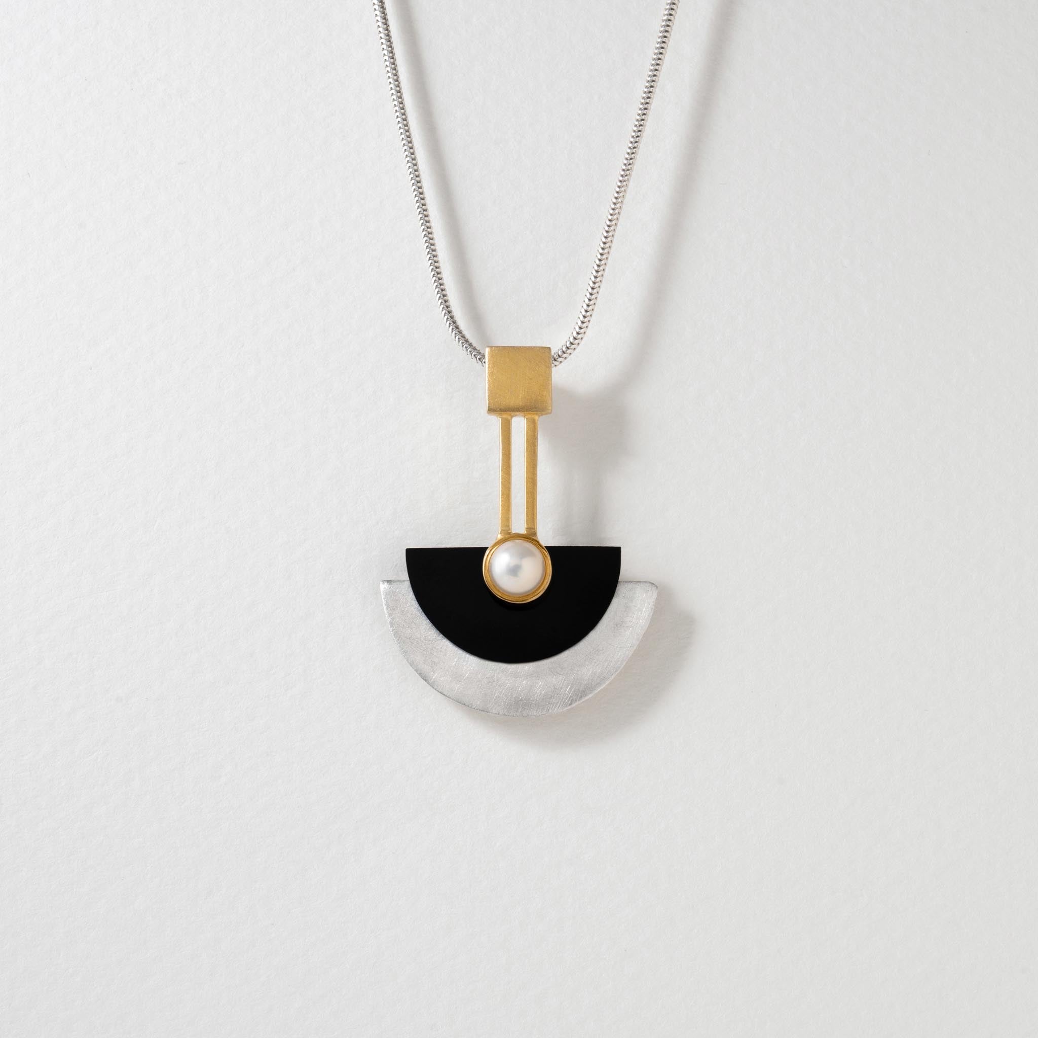 A sterling silver Art Deco necklace with gold plating, featuring a pearl and black resin pendant