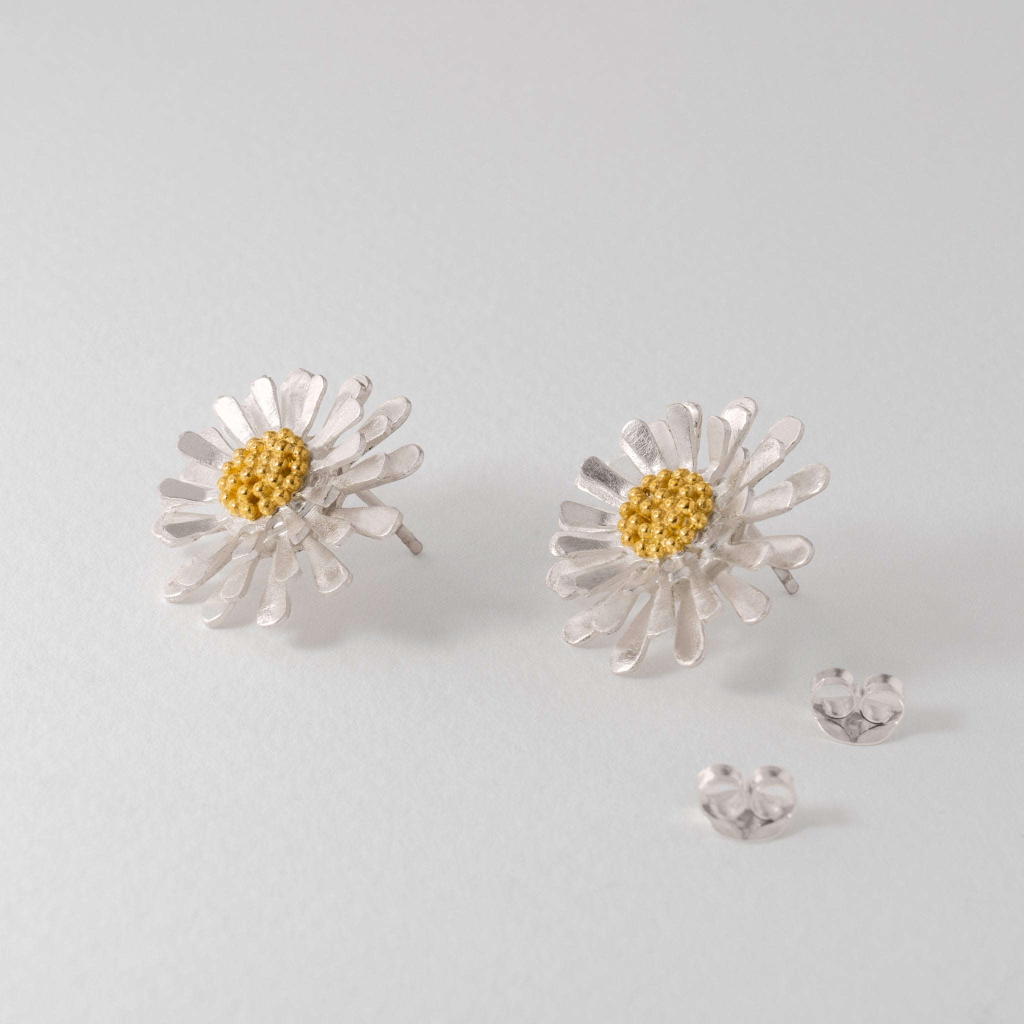A pair of aster flower stud earrings with silver petals and gold centres