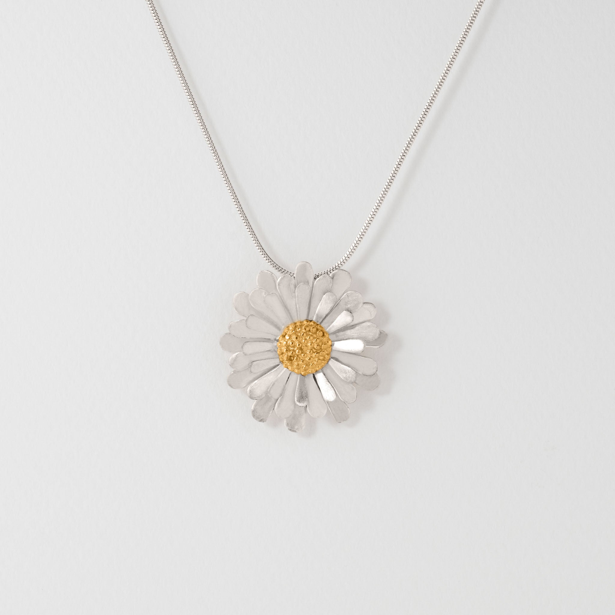 A silver aster flower pendant necklace with an 18 carat gold plated centre
