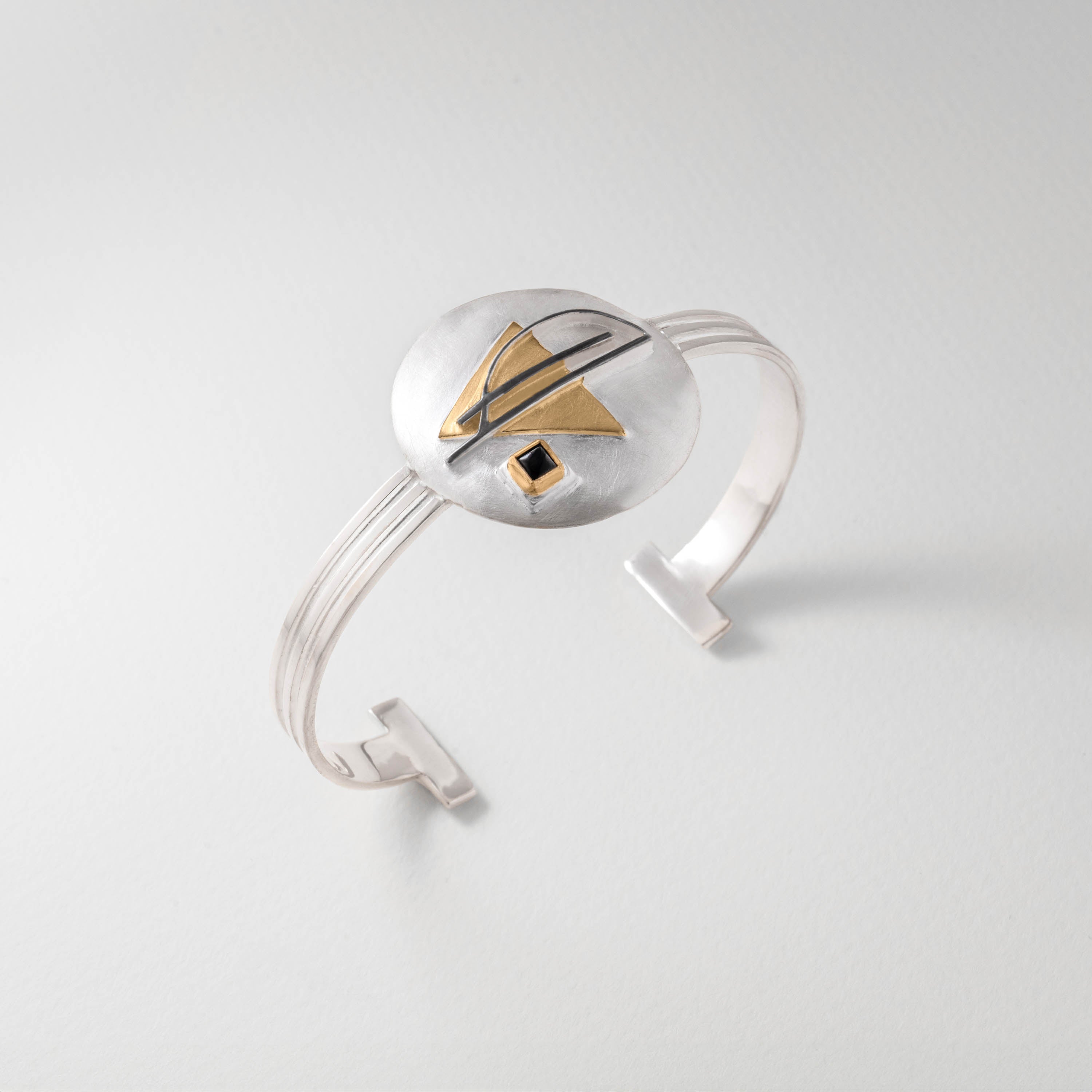 Bauhaus inspired bangle in sterling silver with 18ct gold plate and black onyx. The minimalist design features geometric detailing, reflecting the Bauhaus ethos of pure form, function and modernist elegance.