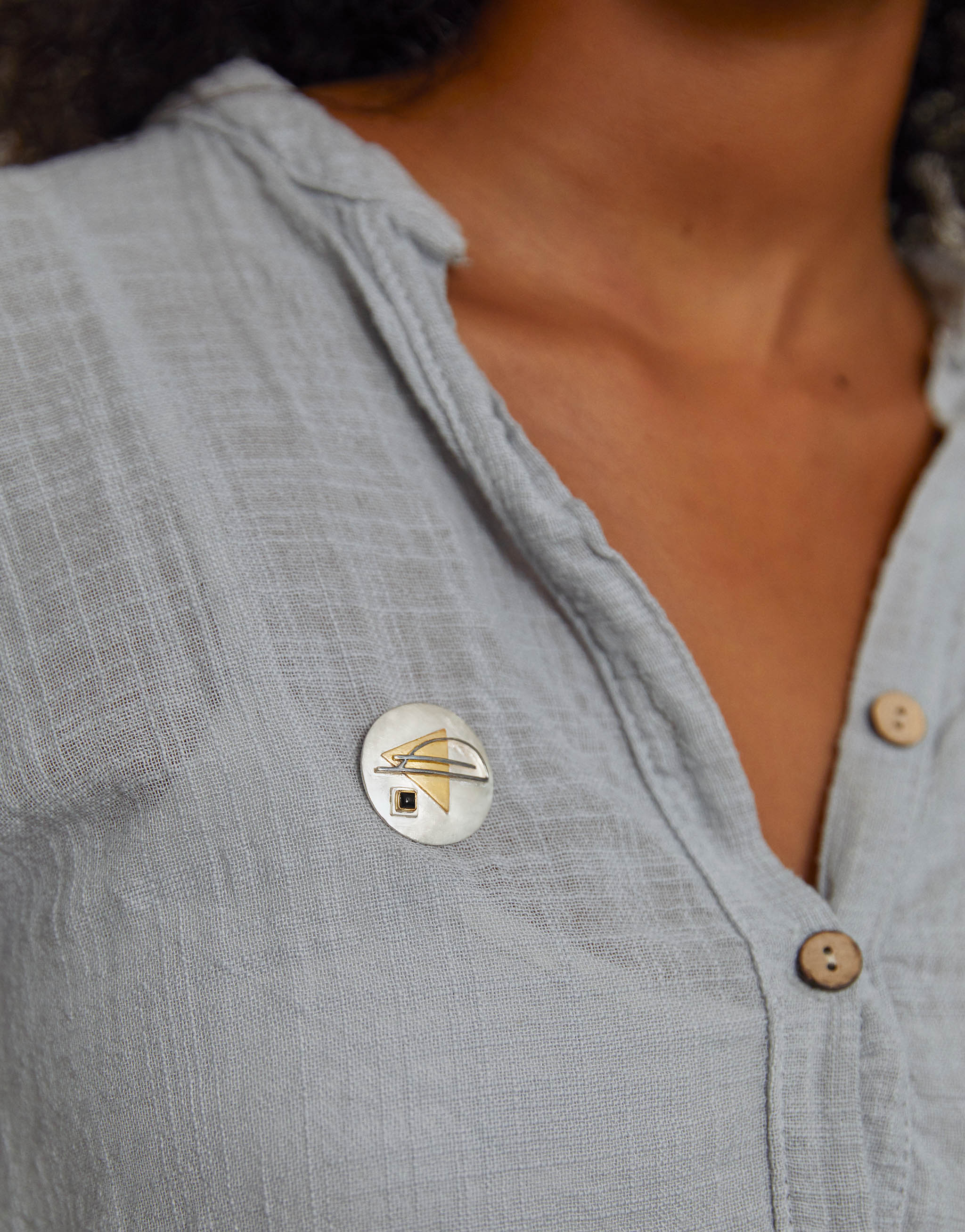 Bauhaus-inspired 2-in-1 brooch and necklace in sterling silver with gold-plated accents and a black onyx detail. The round design features bold geometric lines and shapes, reflecting the Bauhaus balance of form and function.