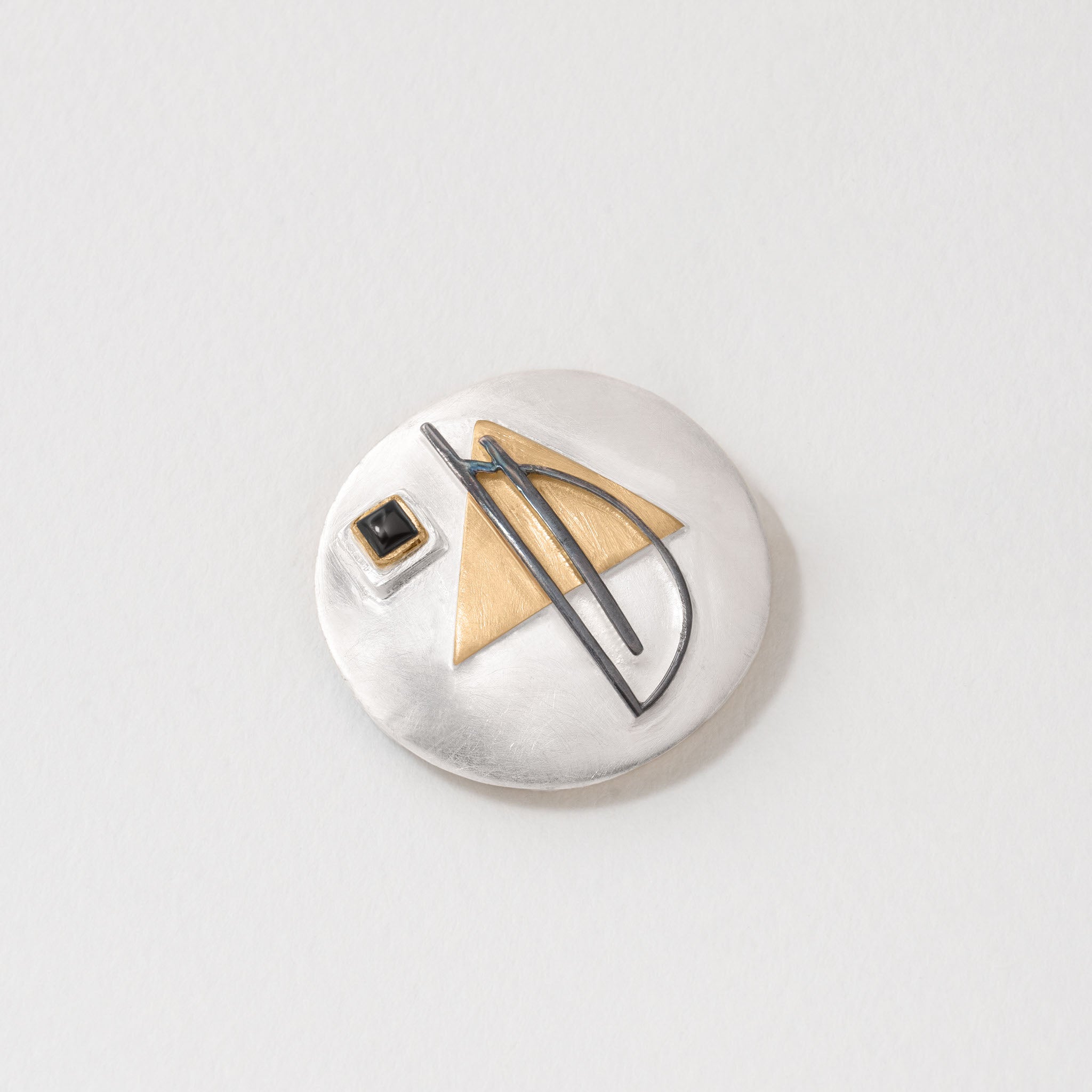 Sterling silver Bauhaus brooch and necklace pendant with circular form, featuring a gold-plated triangle, black enamel line detail, and square black onyx stone. The versatile design reflects Bauhaus minimalism and can be worn as either a brooch or pendant.