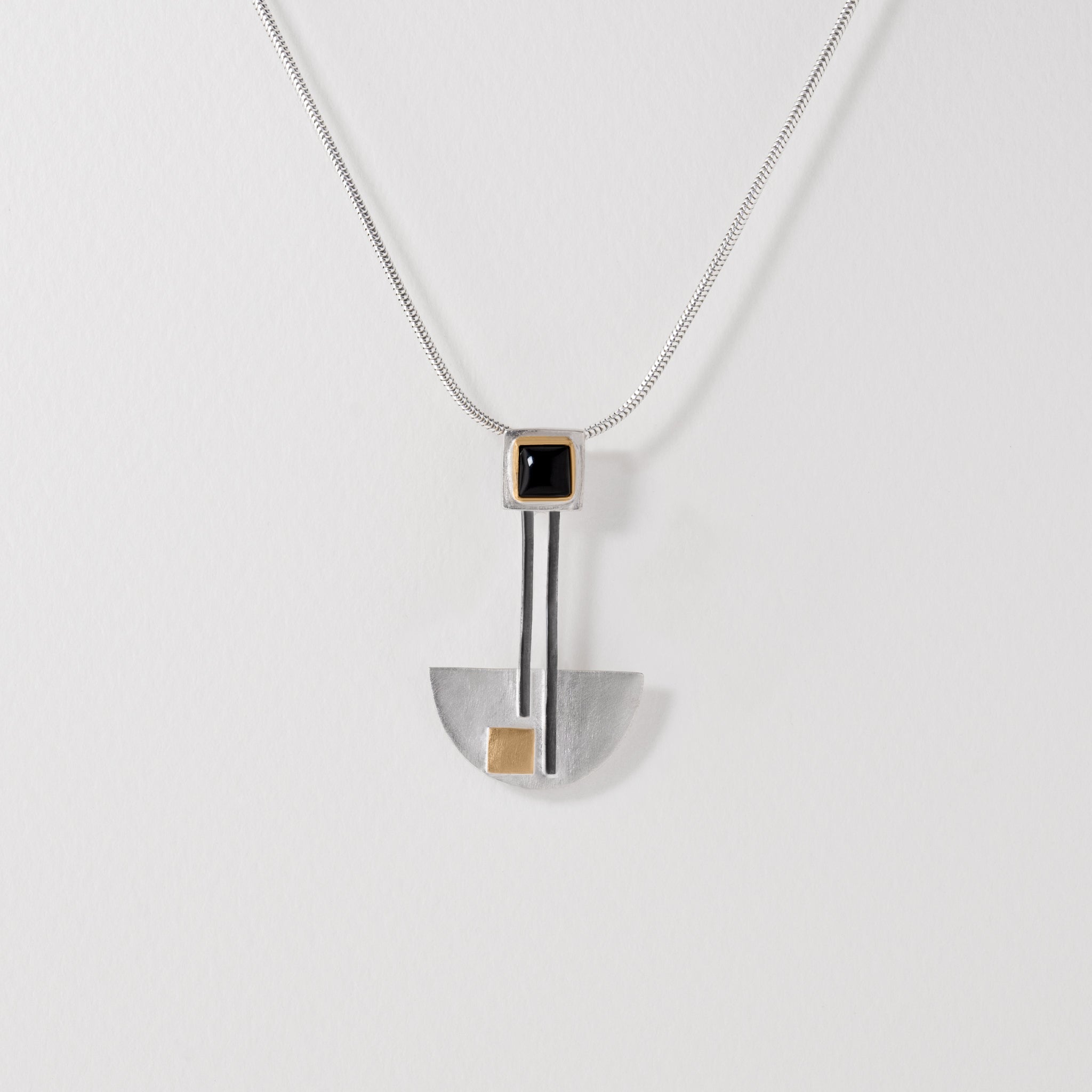 Bauhaus inspired pendant necklace in sterling silver with 18ct gold plated accents and black onyx. Minimalist geometric jewellery celebrating Bauhaus design principles.