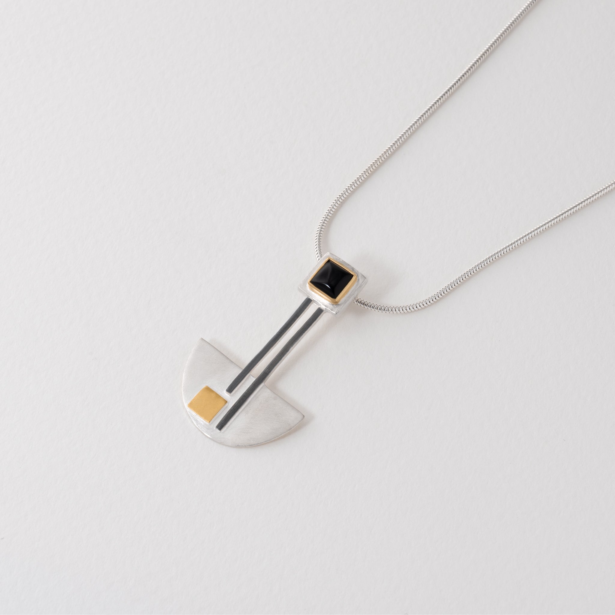 Geometric Bauhaus necklace with sterling silver pendant, gold-plated accents and black onyx stone. Modern minimalist jewellery inspired by Bauhaus artistry.