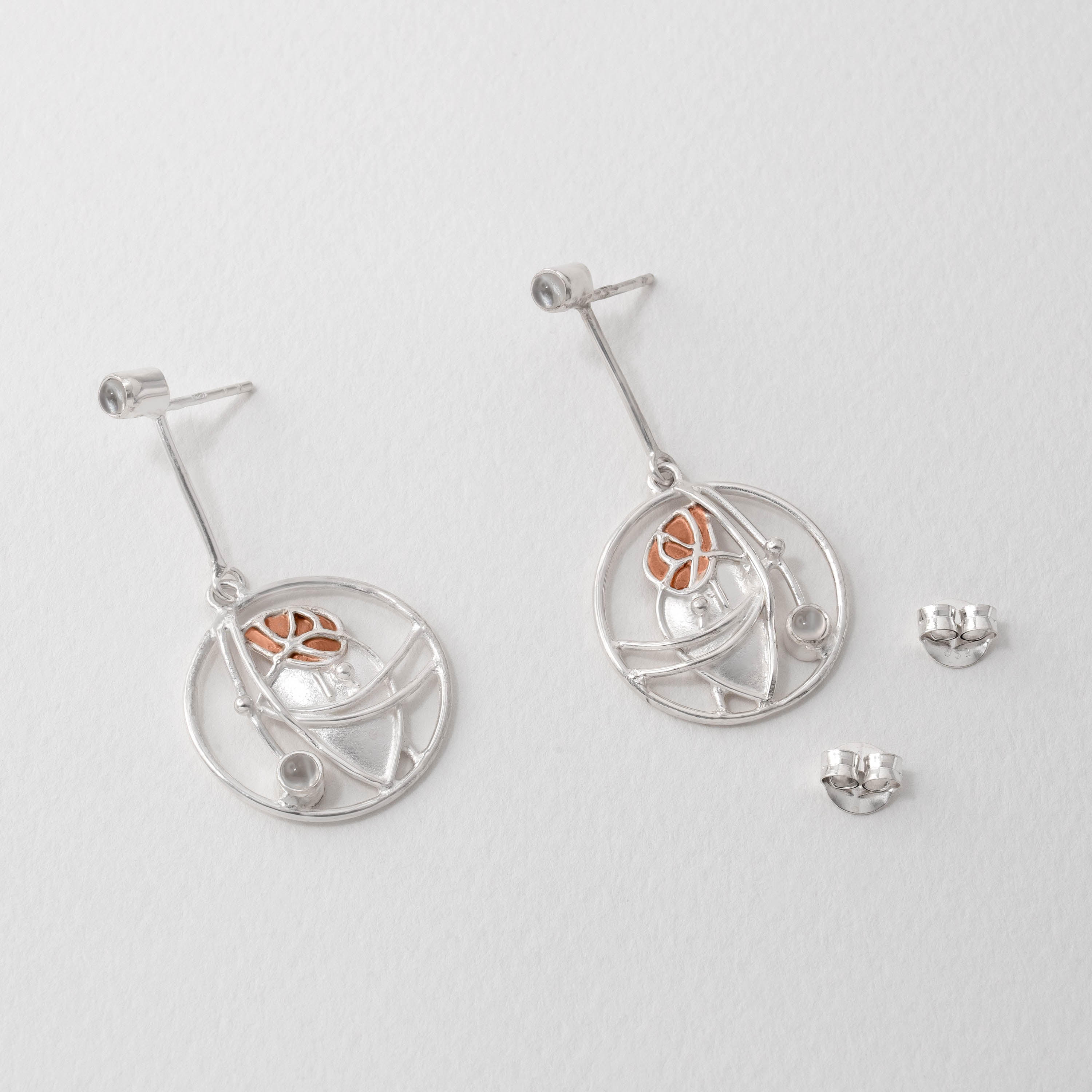 Charles Rennie Mackintosh inspired moonstone pendant necklace in sterling silver with copper detailing. The flowing Art Nouveau design reinterprets his stained-glass panels, set with a luminous moonstone for a sophisticated statement piece.