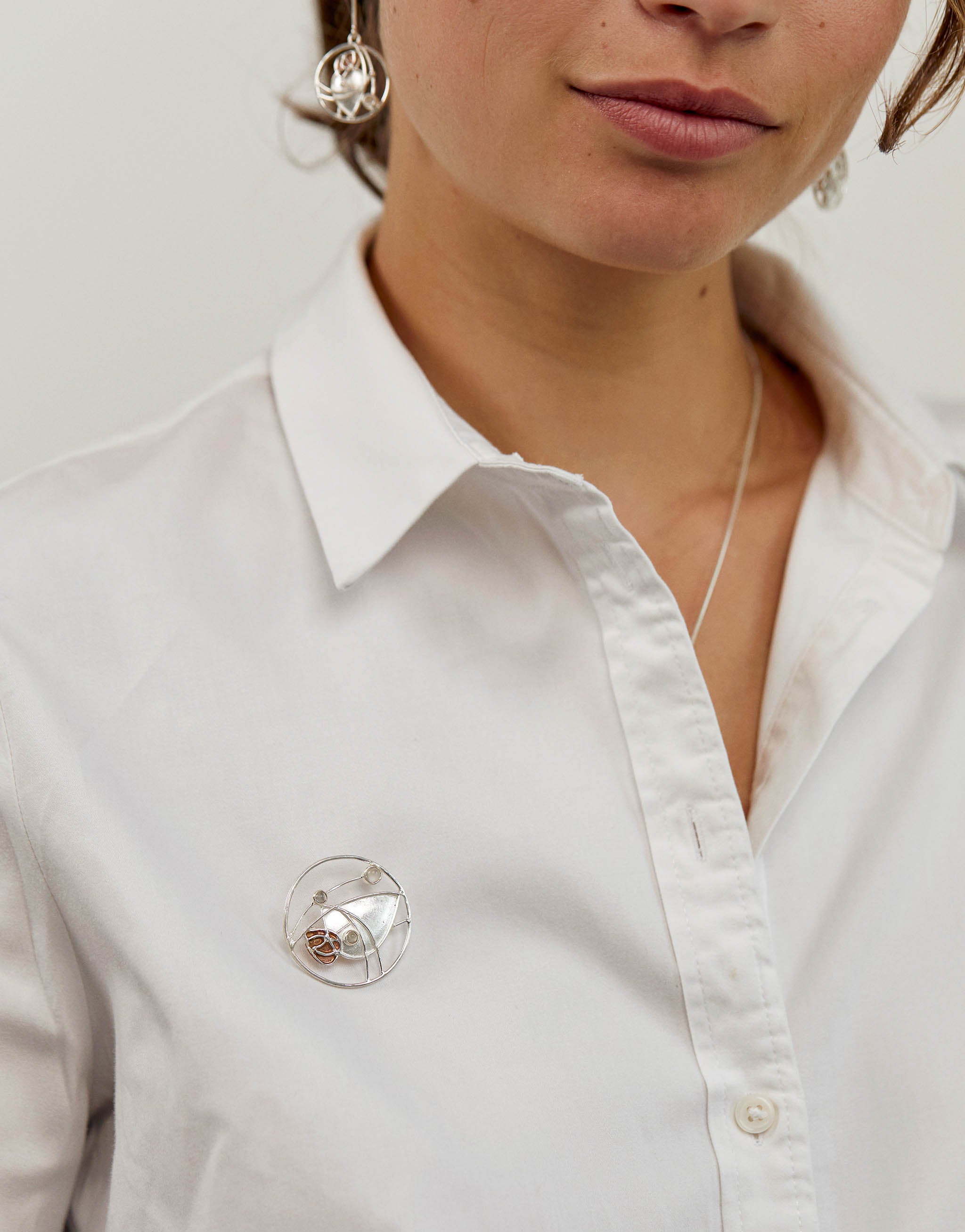 Art Nouveau brooch inspired by Charles Rennie Mackintosh, crafted in sterling silver and copper with a moonstone centre, reimagining his iconic stained-glass motifs.