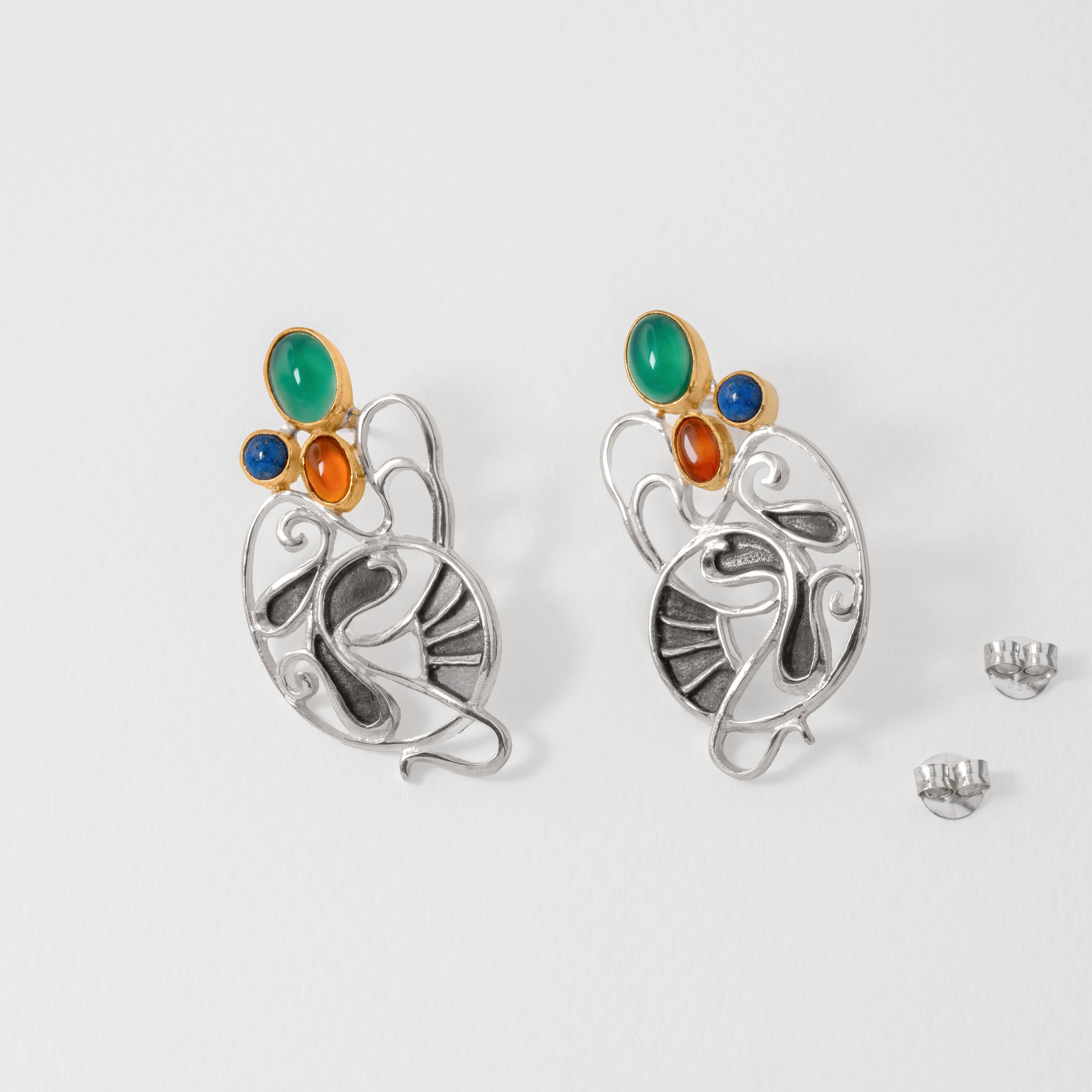 Sterling silver Gaudí earrings with fluid Modernist curves, accented by green agate, amber and lapis lazuli gemstones. Inspired by Gaudí’s imaginative architecture, they capture his surreal blend of nature and design.
