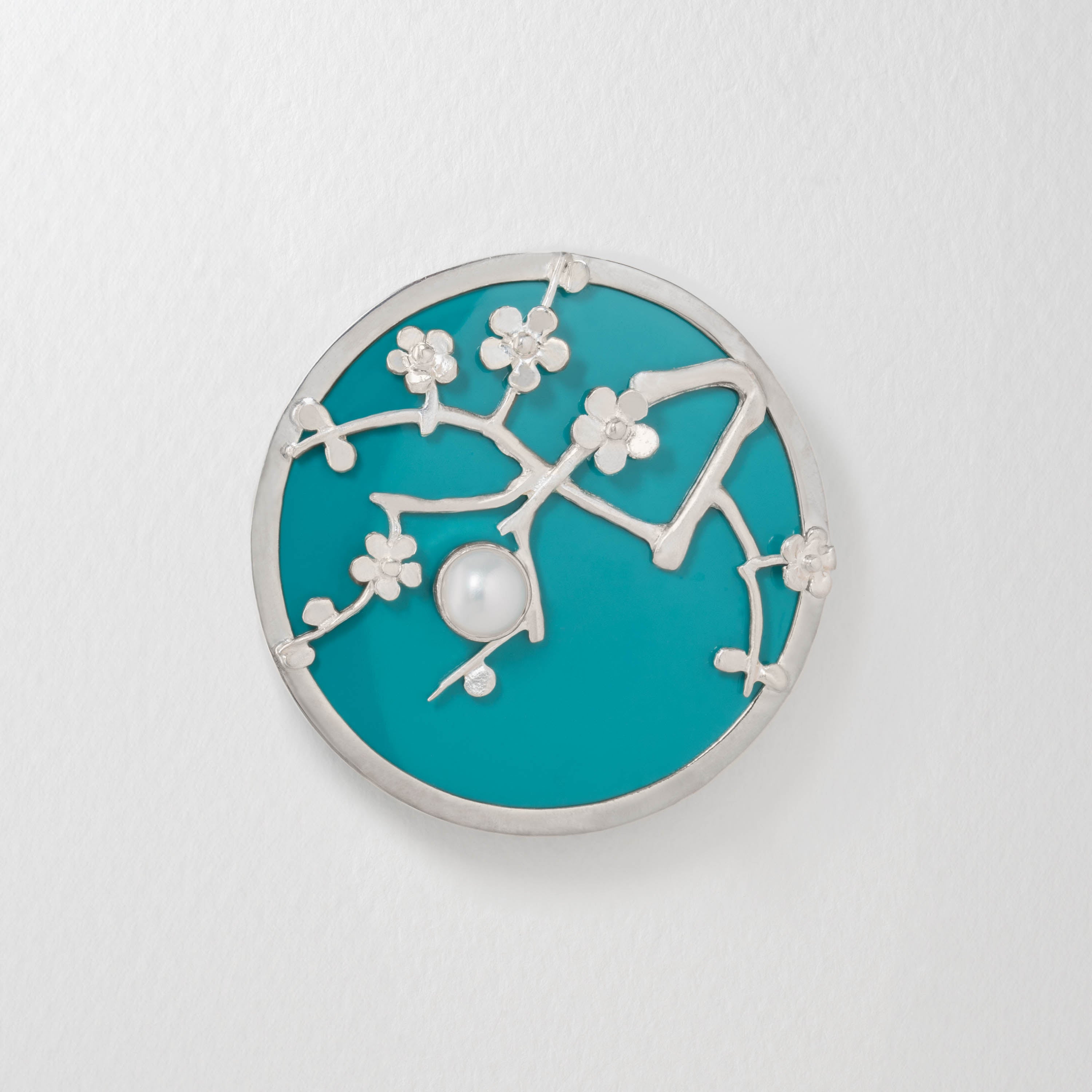 Van Gogh Almond Blossom inspired brooch in sterling silver with turquoise blue resin. Featuring delicate silver branches and blossoms with a central pearl-like detail, the design captures the impressionist beauty of Van Gogh’s iconic painting.