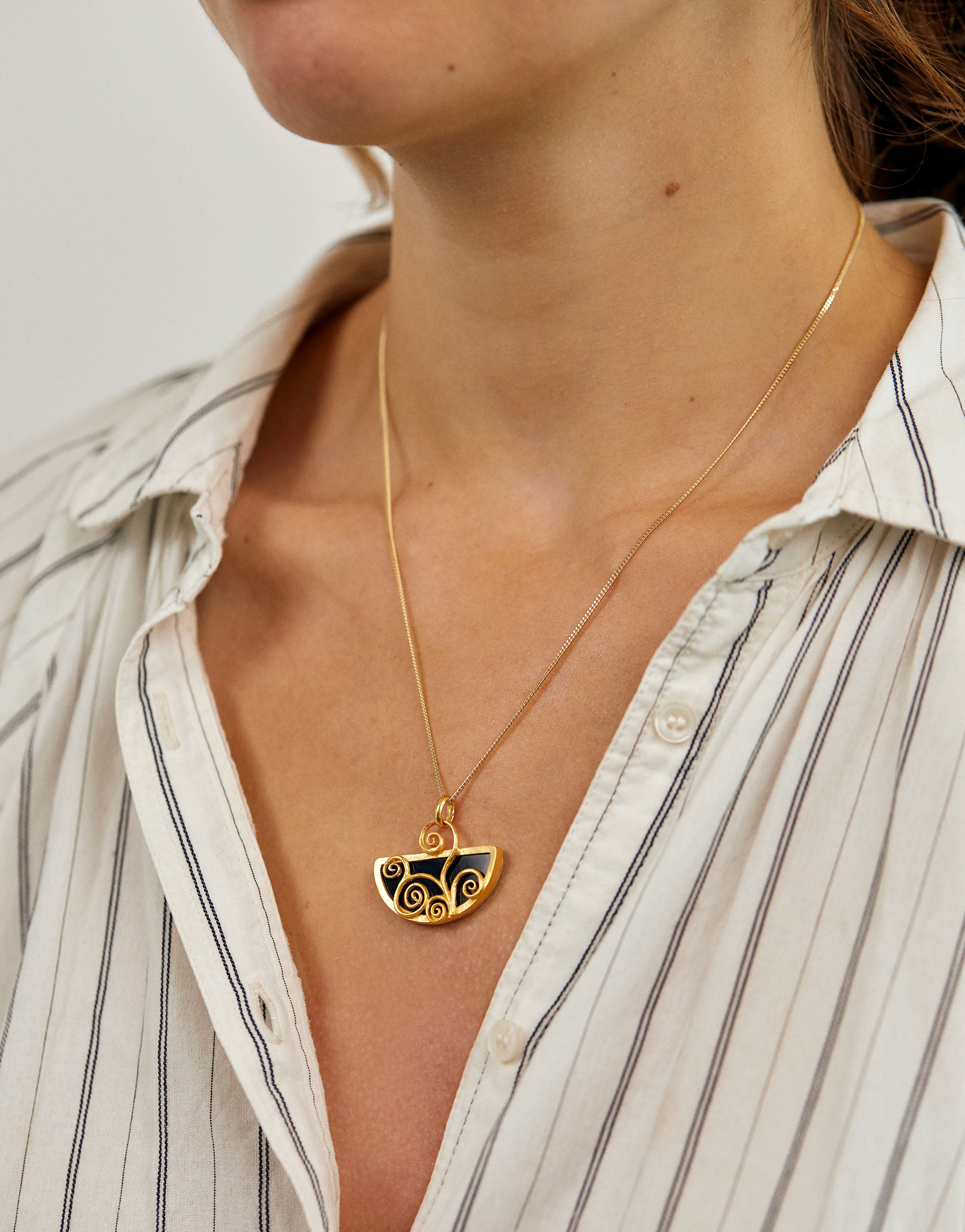 Gustav Klimt style pendant necklace featuring swirling gold design with black resin.