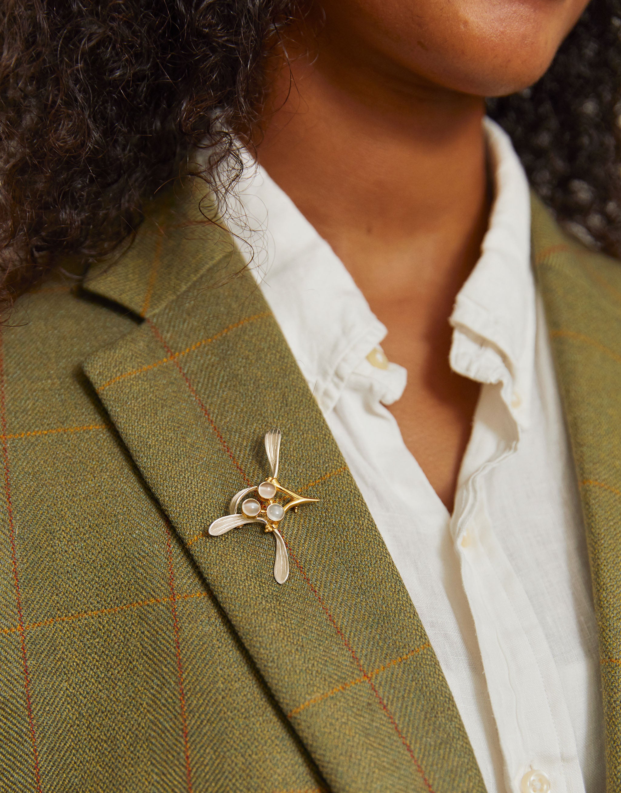 Nature-inspired mistletoe brooch in silver and gold with moonstone gemstones.