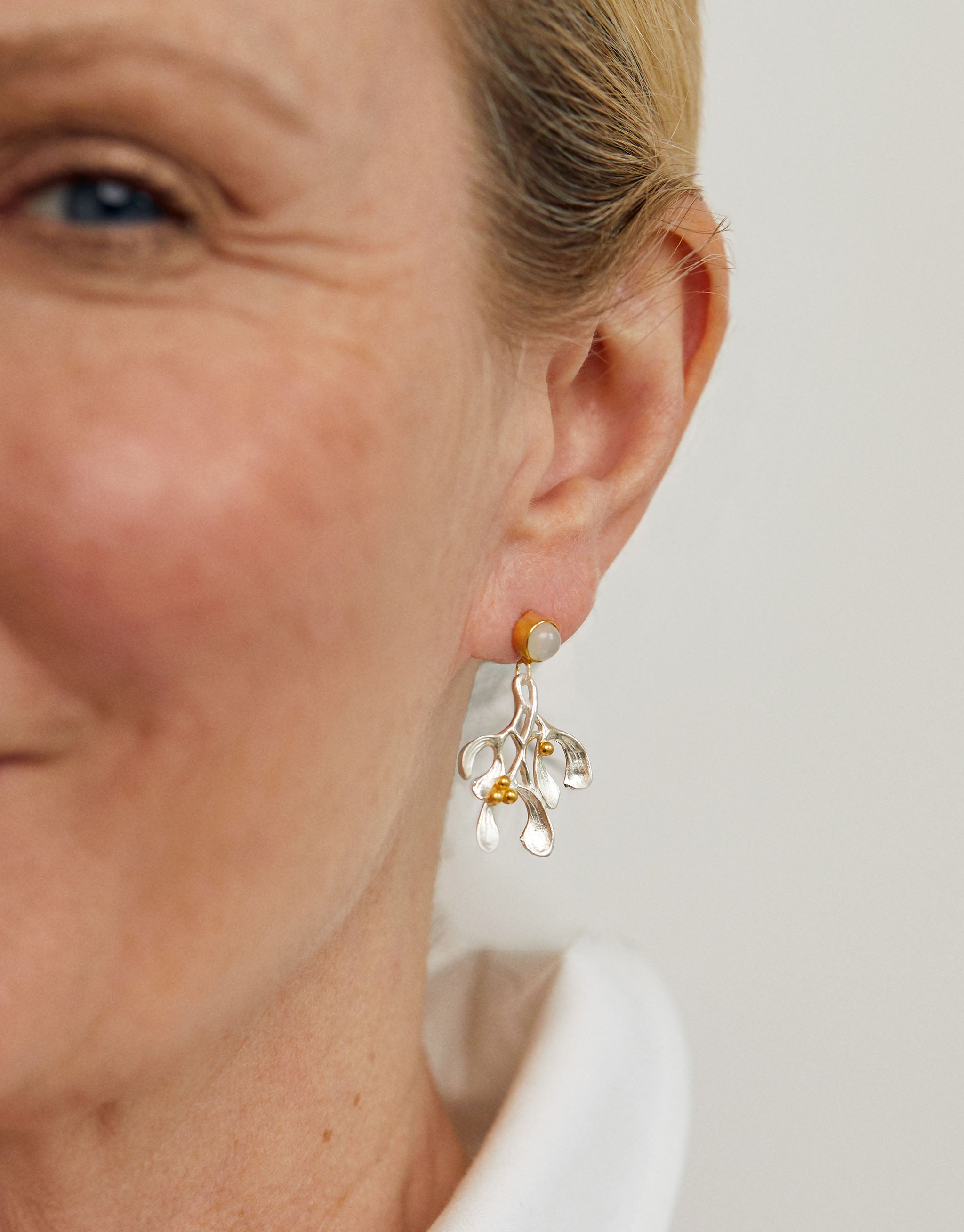 Festive silver and gold mistletoe earrings with radiant moonstone gemstones.