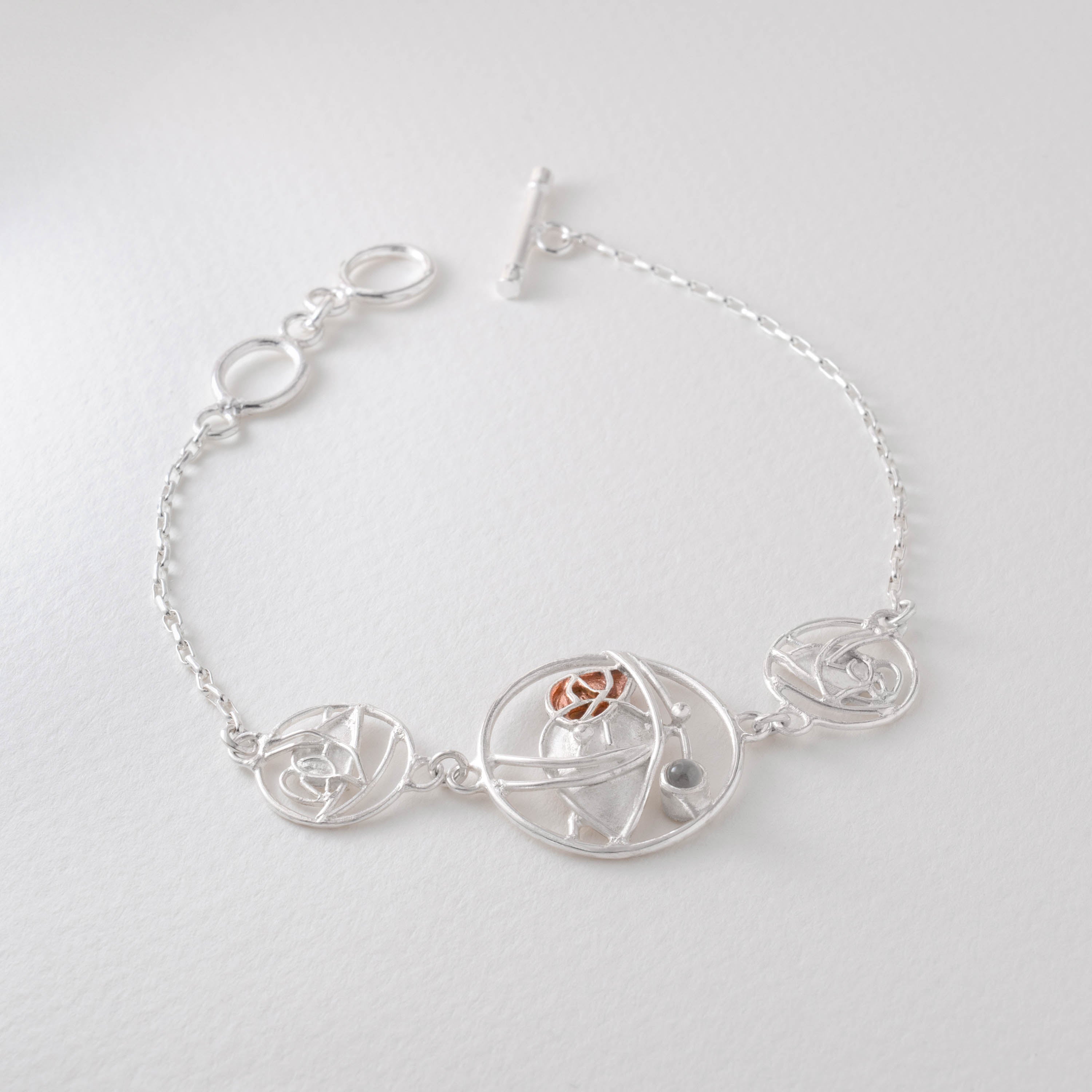A silver-colored Art Nouveau bracelet with intricate design elements, featuring a central moonstone bead and additional adornments.