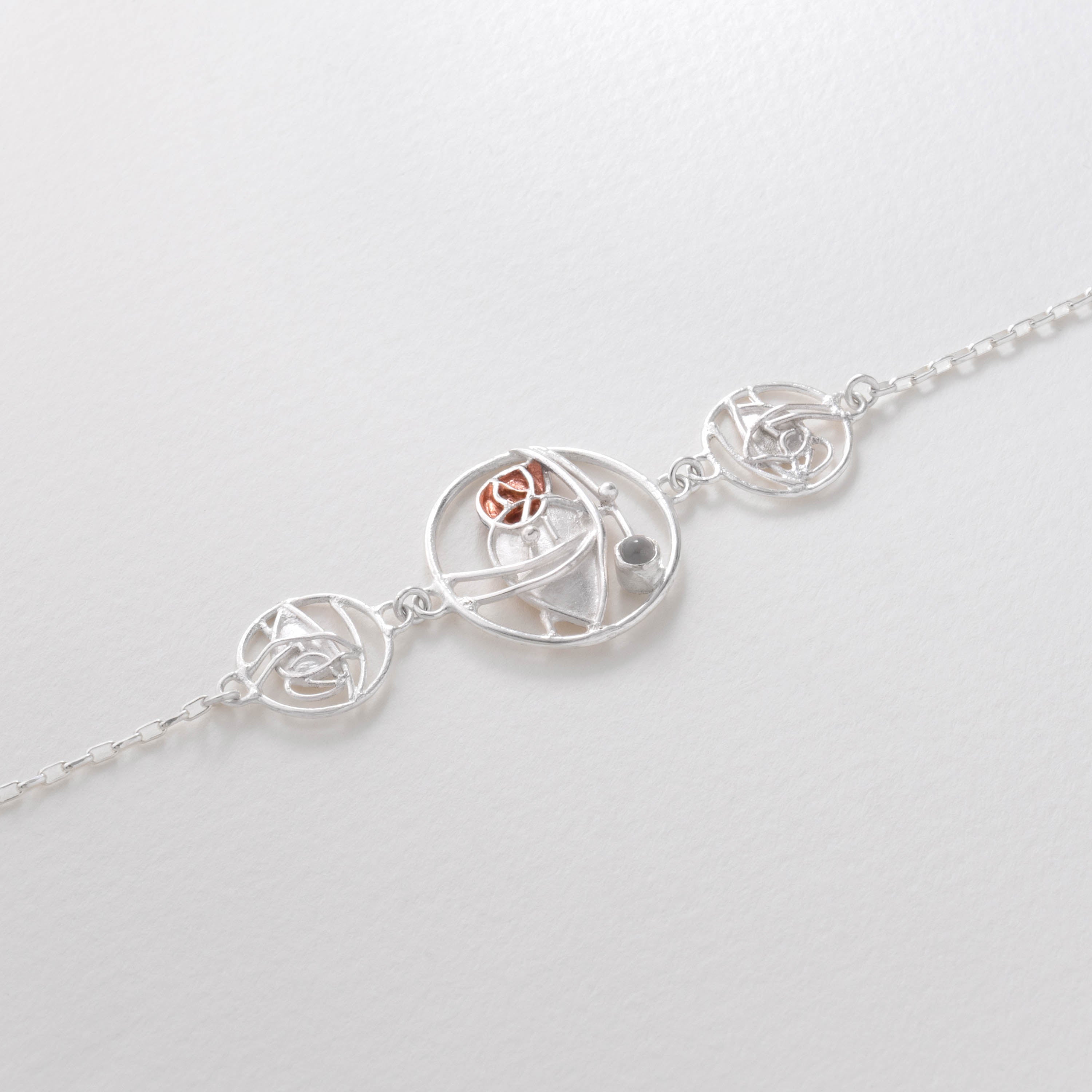 Art Nouveau moonstone necklace inspired by Charles Rennie Mackintosh. Crafted in sterling silver with copper accents, the pendant mirrors the fluid lines of his stained-glass designs, glowing with the elegance of a central moonstone.