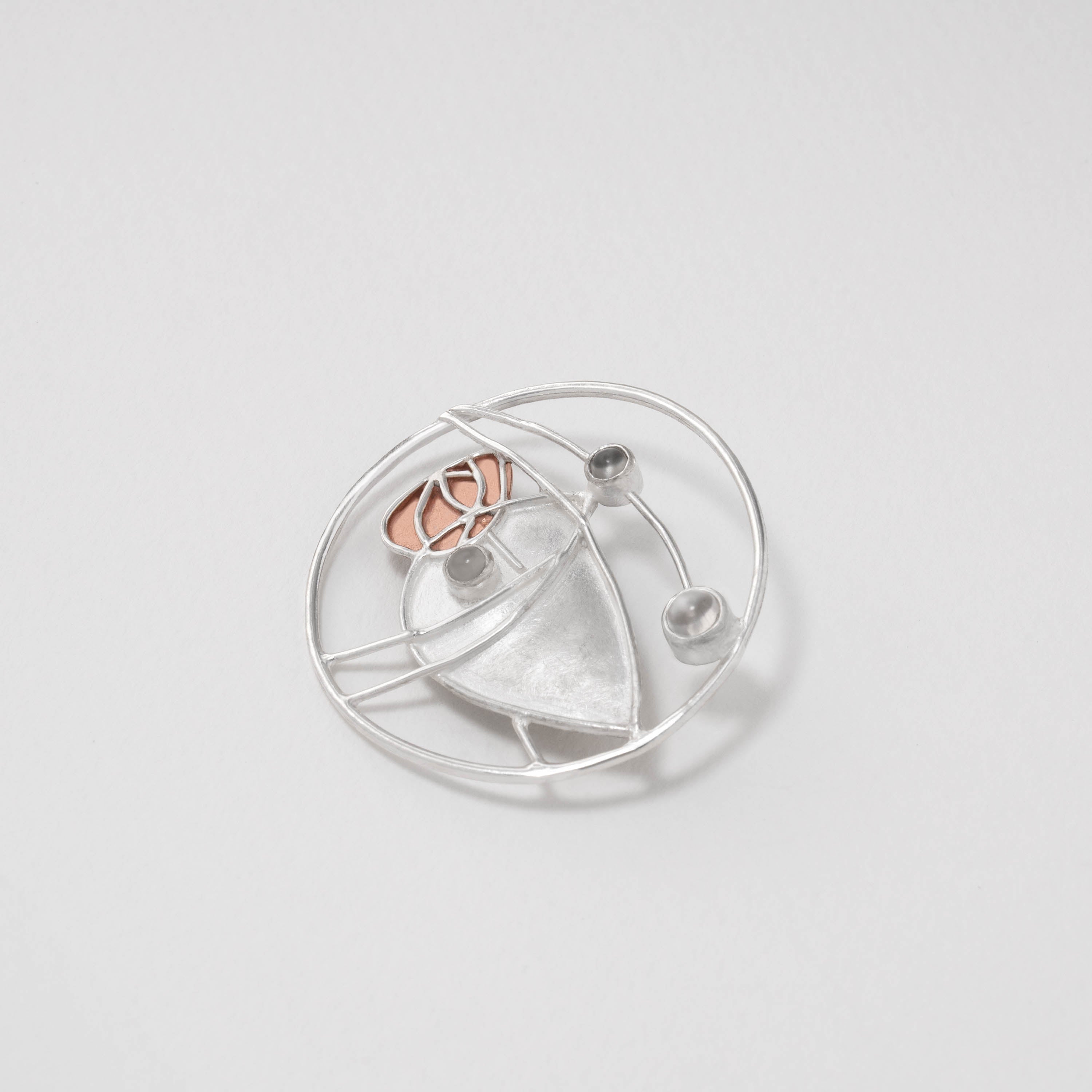 Art Nouveau moonstone brooch inspired by Charles Rennie Mackintosh. Handcrafted in sterling silver with copper detailing, the design captures the fluid elegance of his stained-glass artistry, highlighted by a glowing moonstone centre.