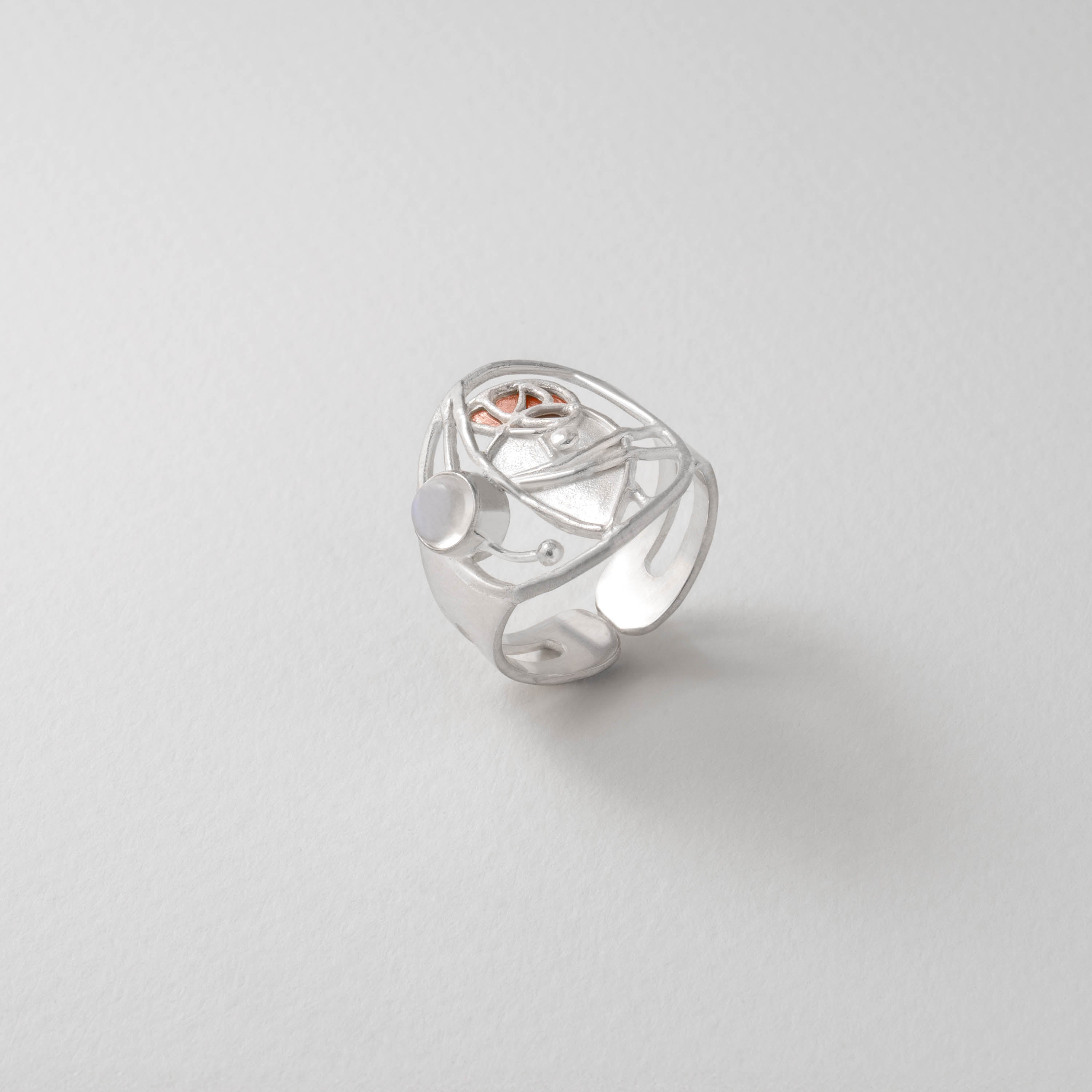 A silver ring with a bronze geometric design, featuring curves that flow in graceful arcs.