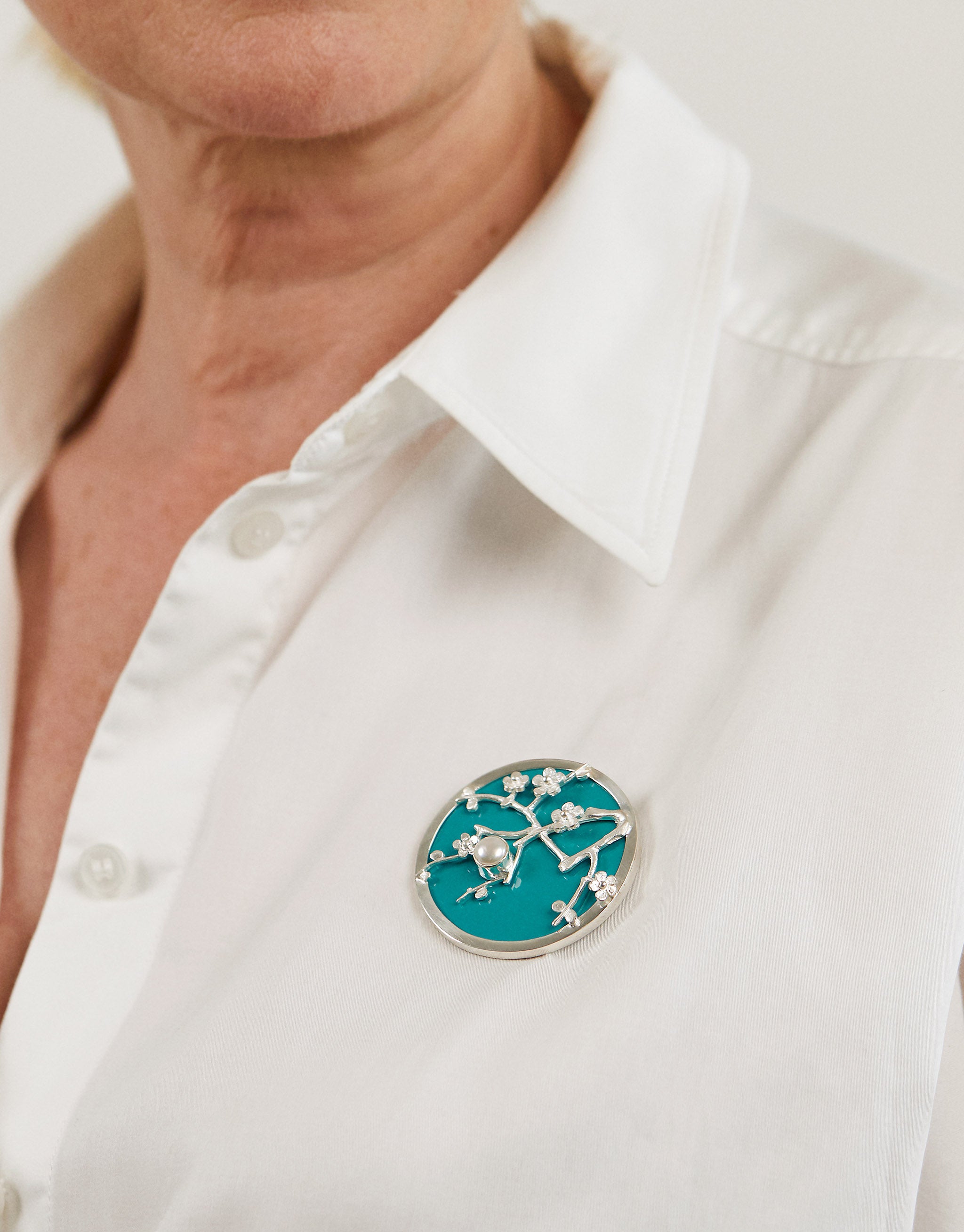 Art-inspired blossom brooch in sterling 925 silver with pearl and vibrant blue resin.