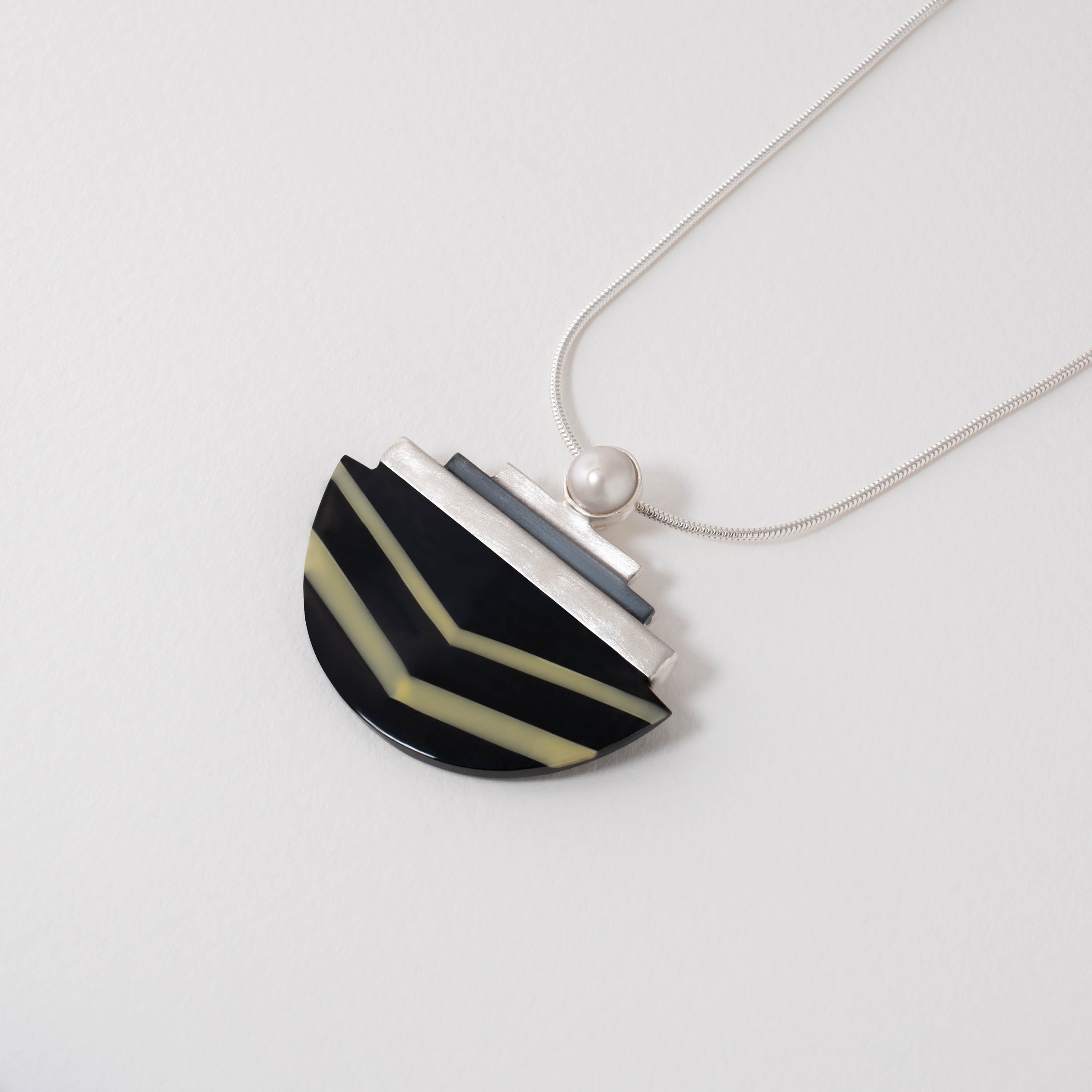 Wiener Werkstätte inspired pendant necklace in sterling silver with black and white resin. The bold geometric design features stepped silver details and a natural pearl accent, reflecting modernist elegance and craftsmanship.