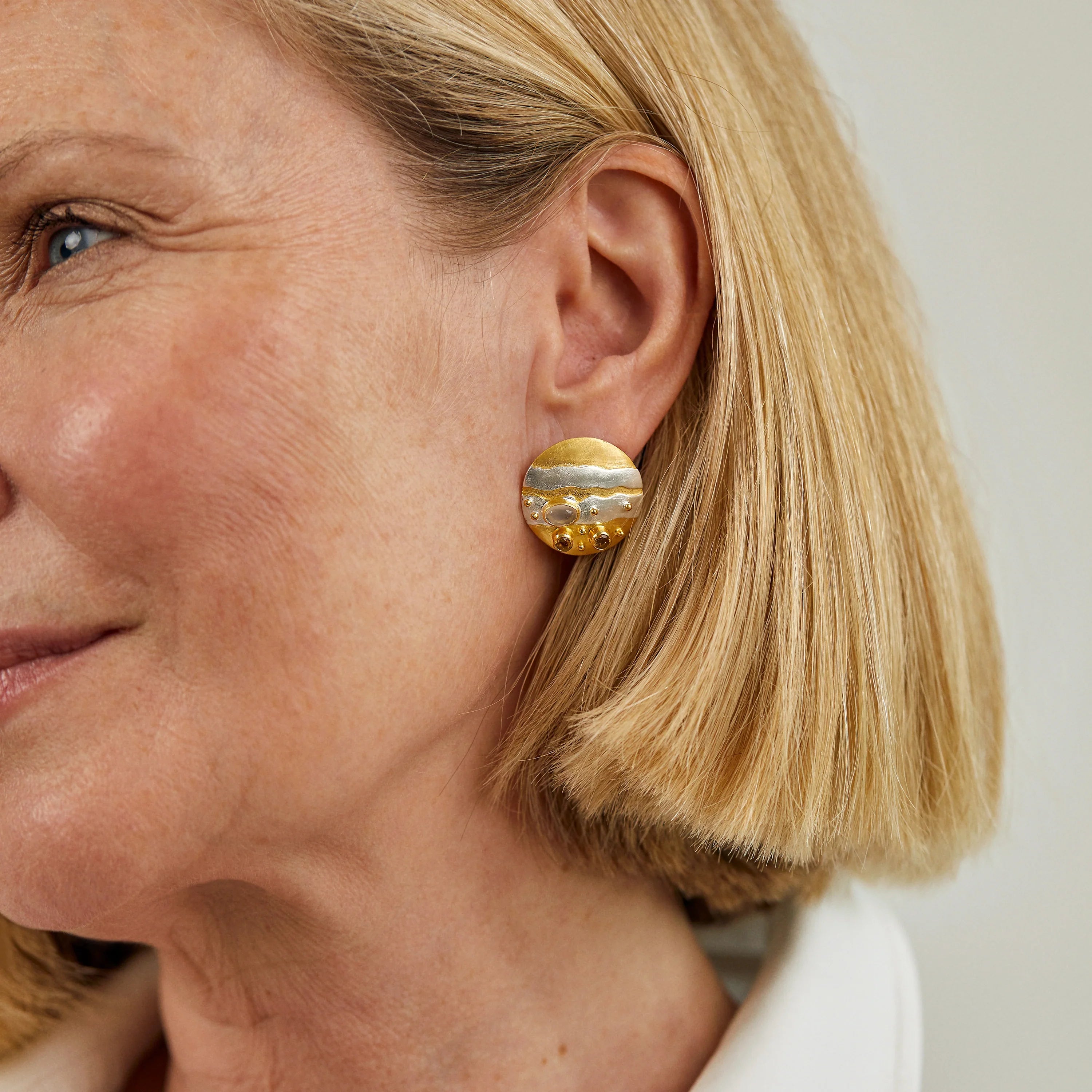mixed metal gold and silver earrings worn on the ear
