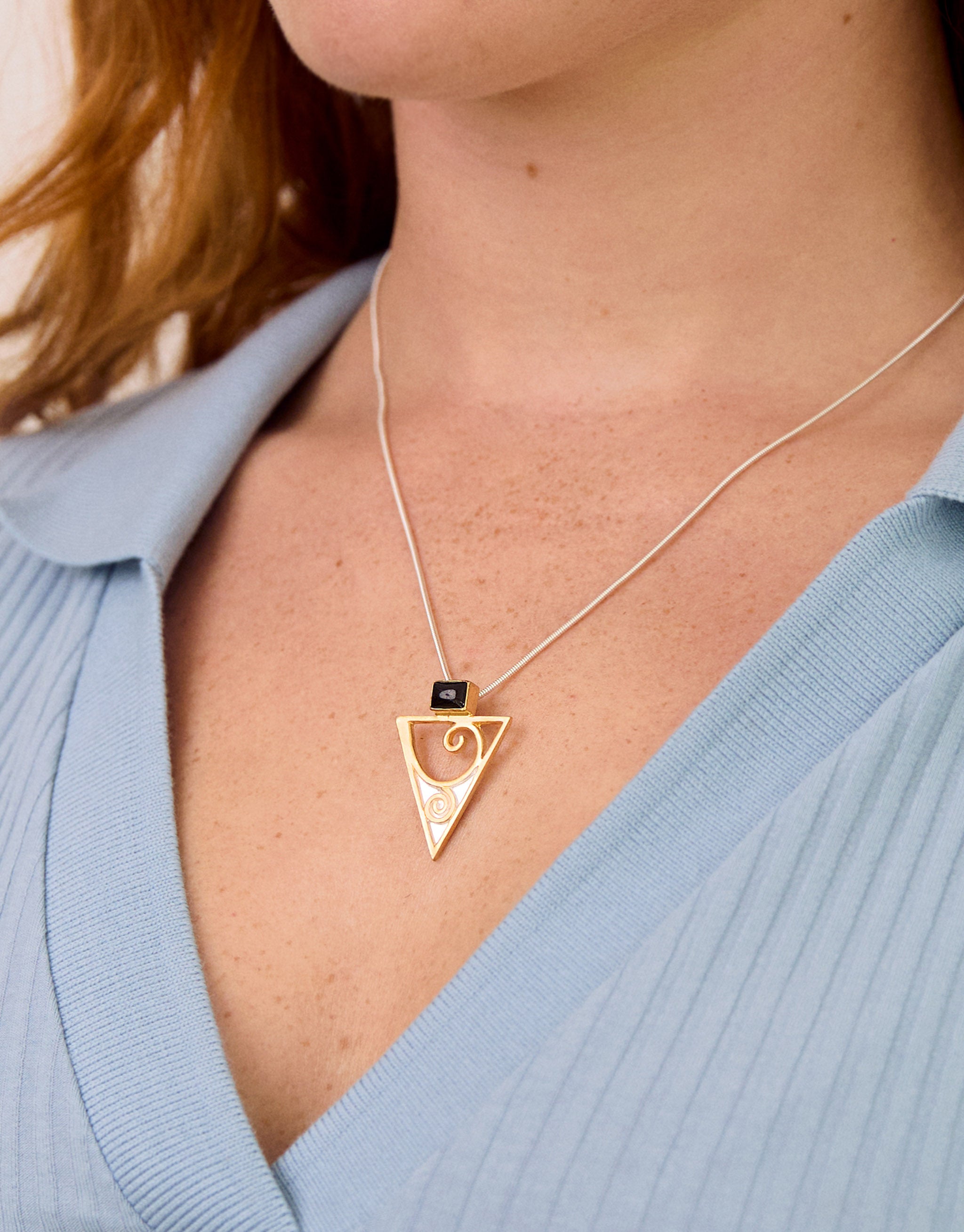 Golden triangular pendant necklace with design inspired by Gustav Klimt. Sterling silver with gold triangle and swirls and black onyx gemstone.