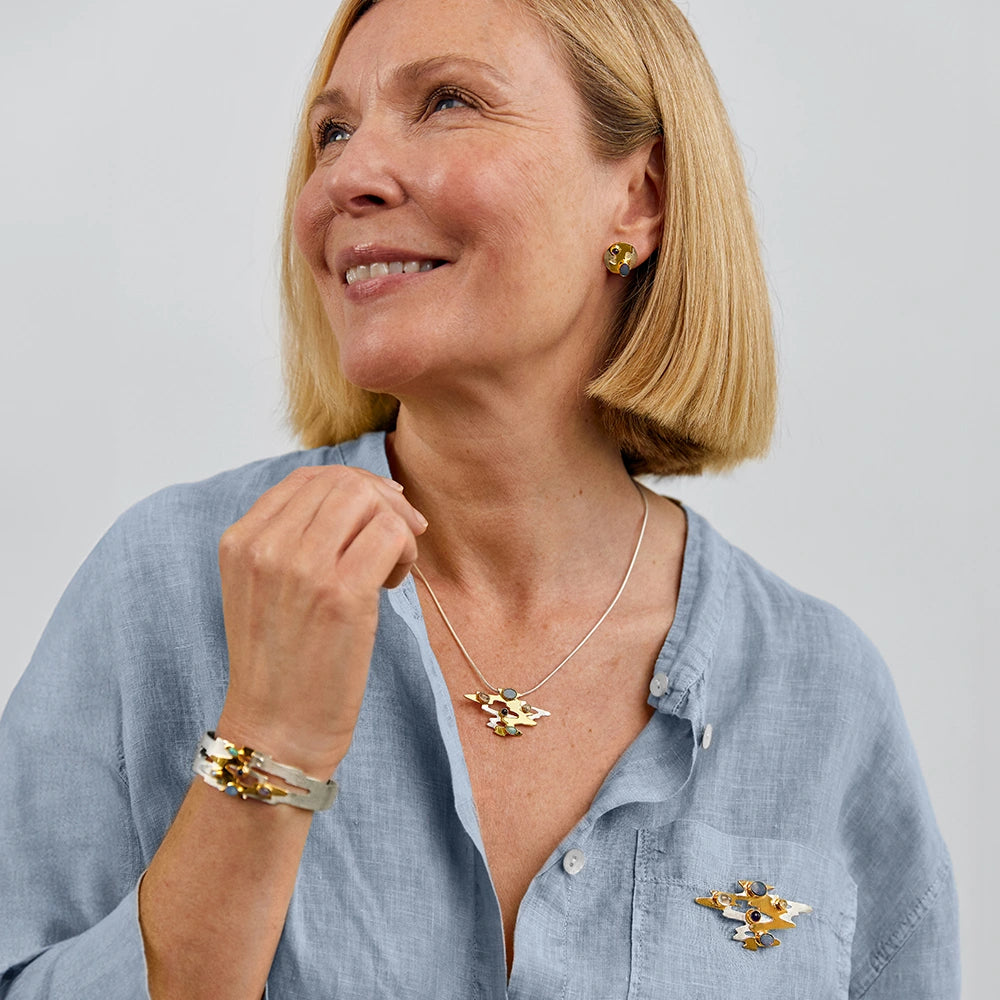 Woman wearing gold and silver opal necklace, brooch, bracelet, and earrings