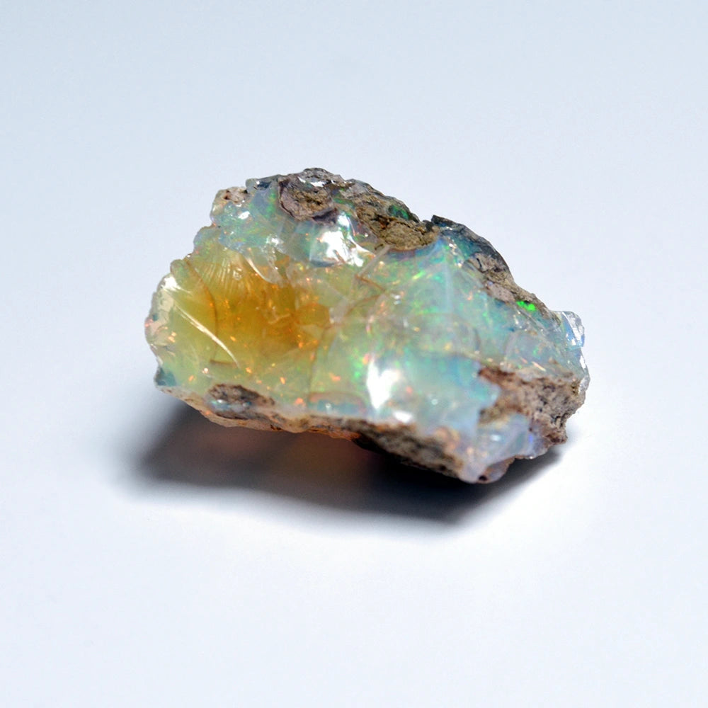 Opal stone with iridescent colors on a light gray background