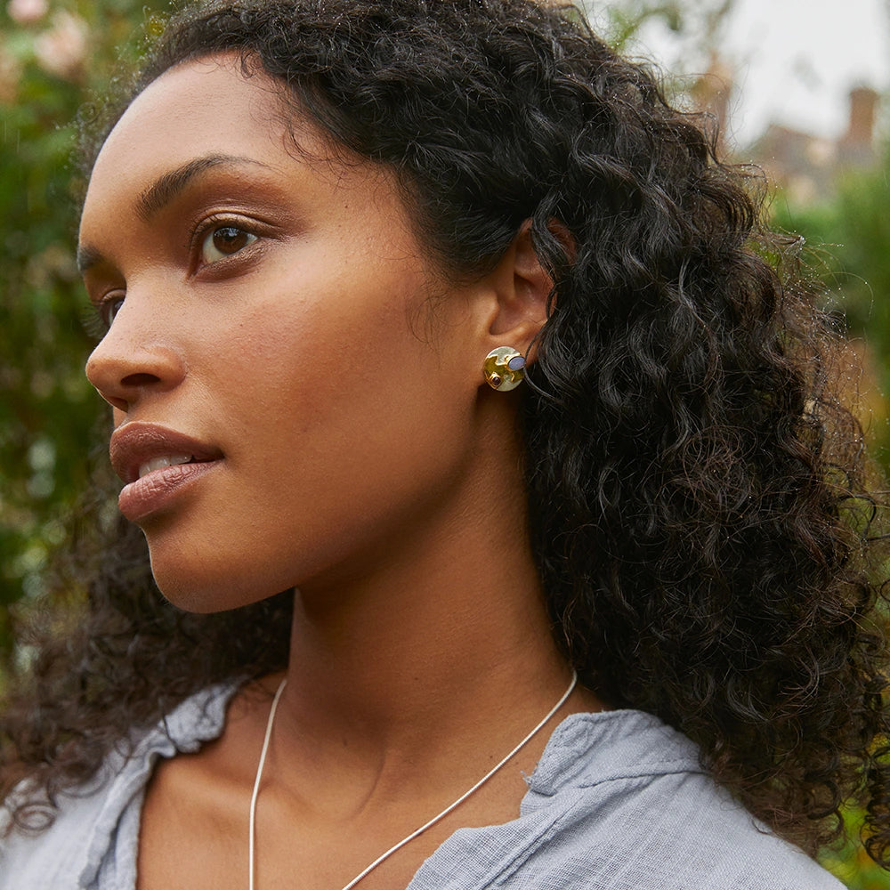Woman wearing gold silver and opal stud earrings