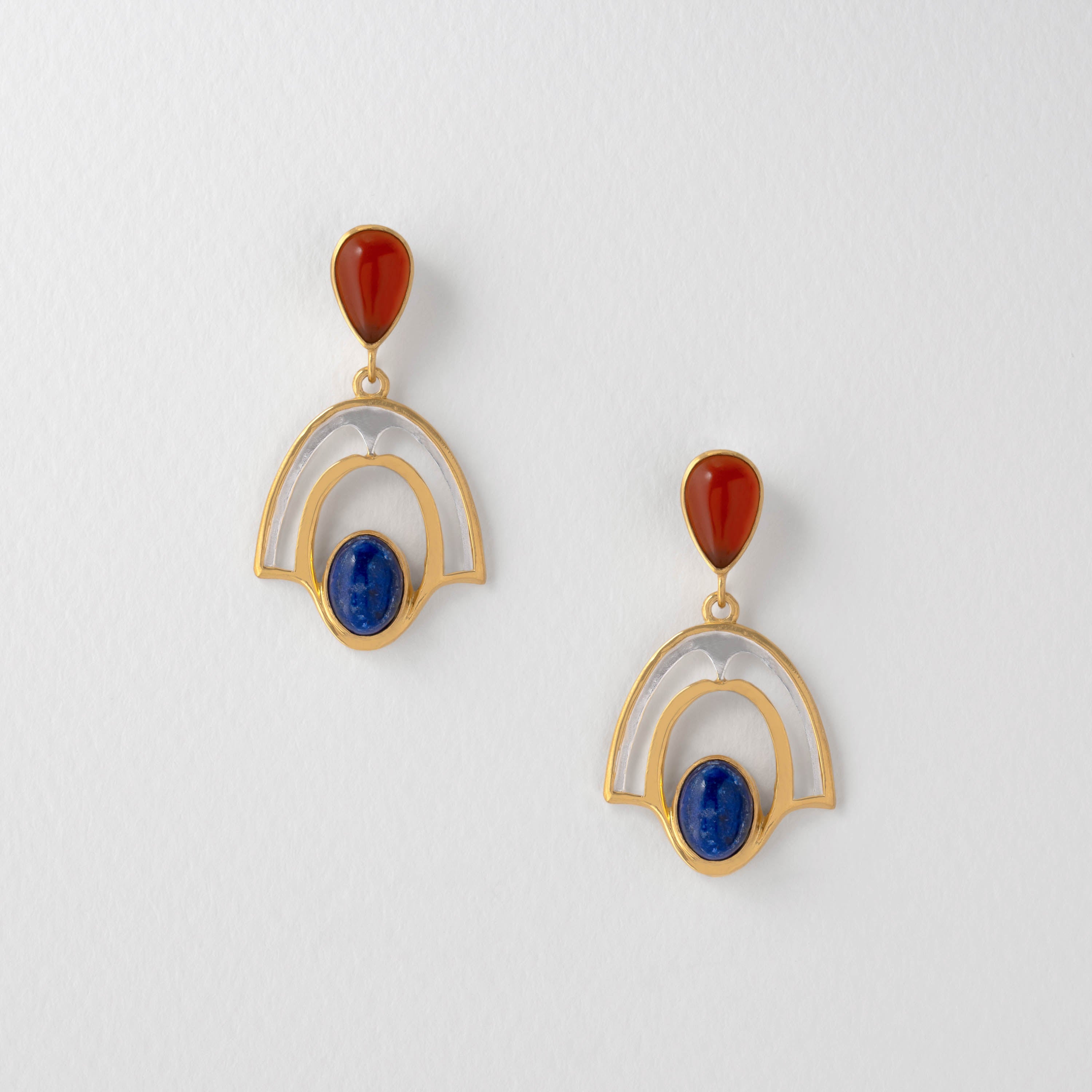 A pair of silver earrings featuring deep blue lapis lazuli and fiery red cornelian, set in gold-plated mountings.