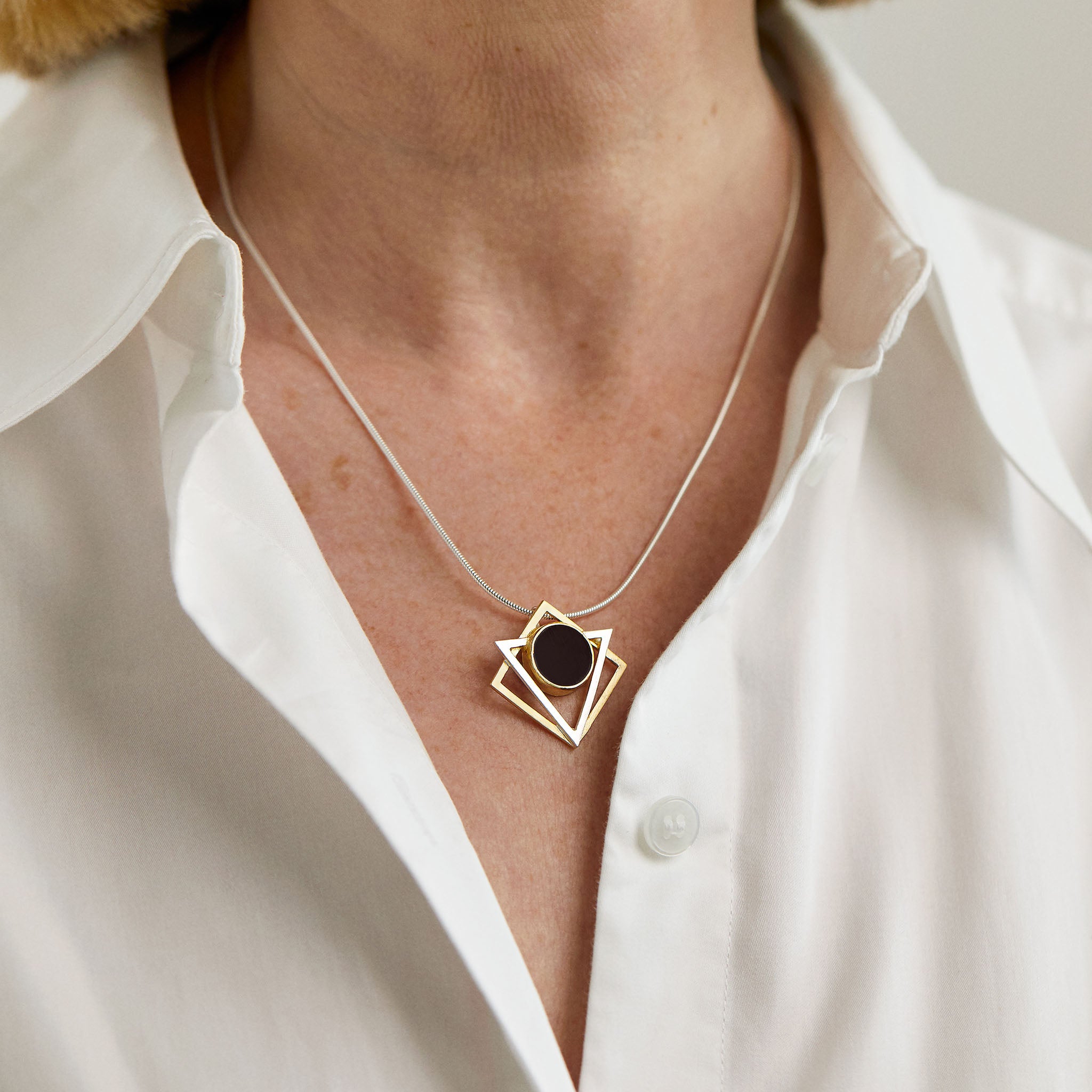 A Klimt-inspired geometric necklace with gold-plated accents and a black resin pendant.