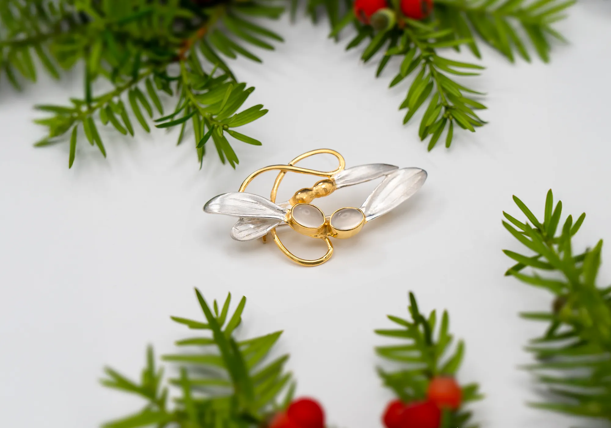 18ct Gold and silver sycamore pod brooch with moonstone details against a winter background.